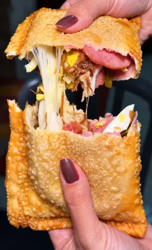 Pastel aberto, bem recheado de carne seca, presunto, ovo, azeitona e queijo